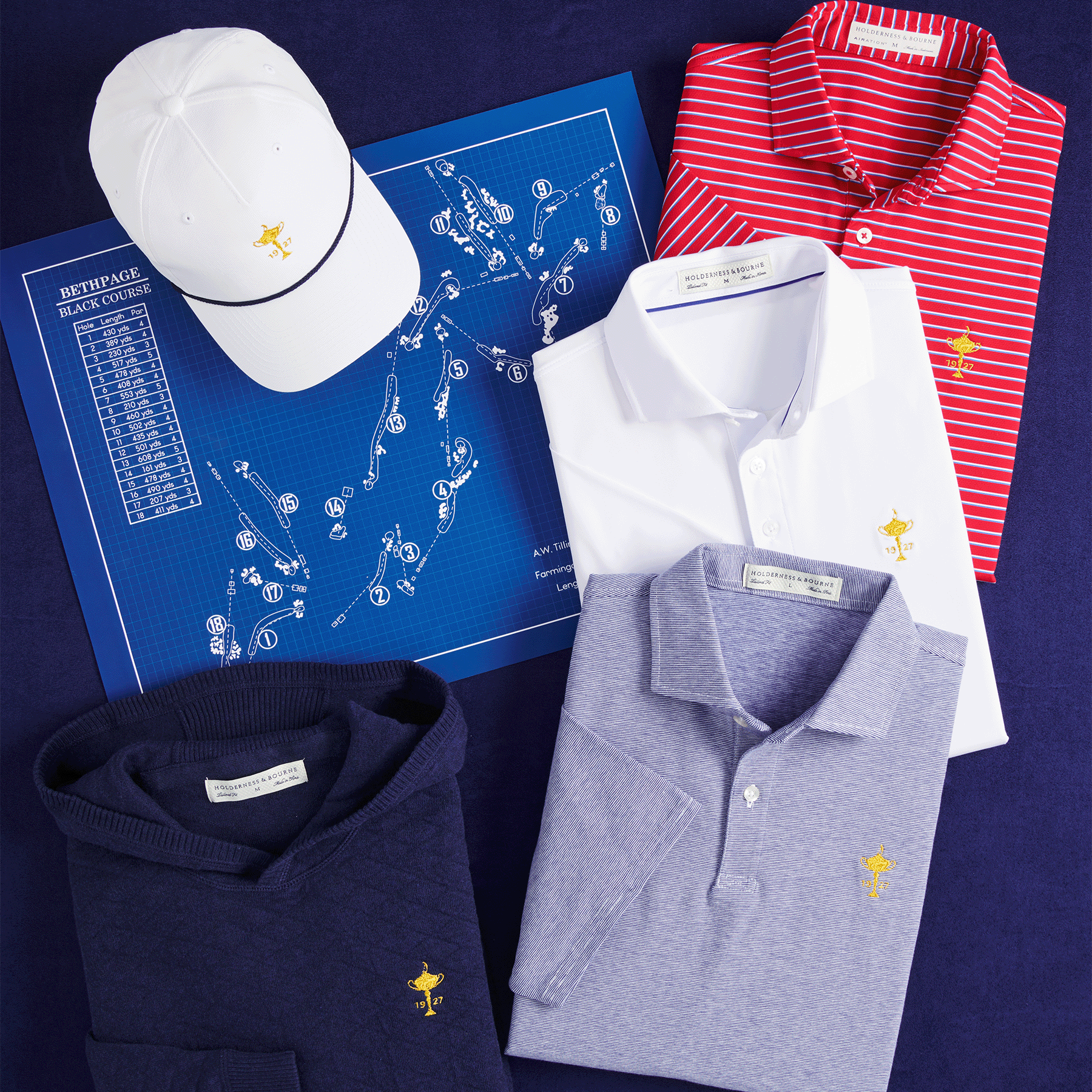 Flat lay of Ryder Cup embroidered polos, a hooded sweater and a white cap around a blue Bethpage Black course map.