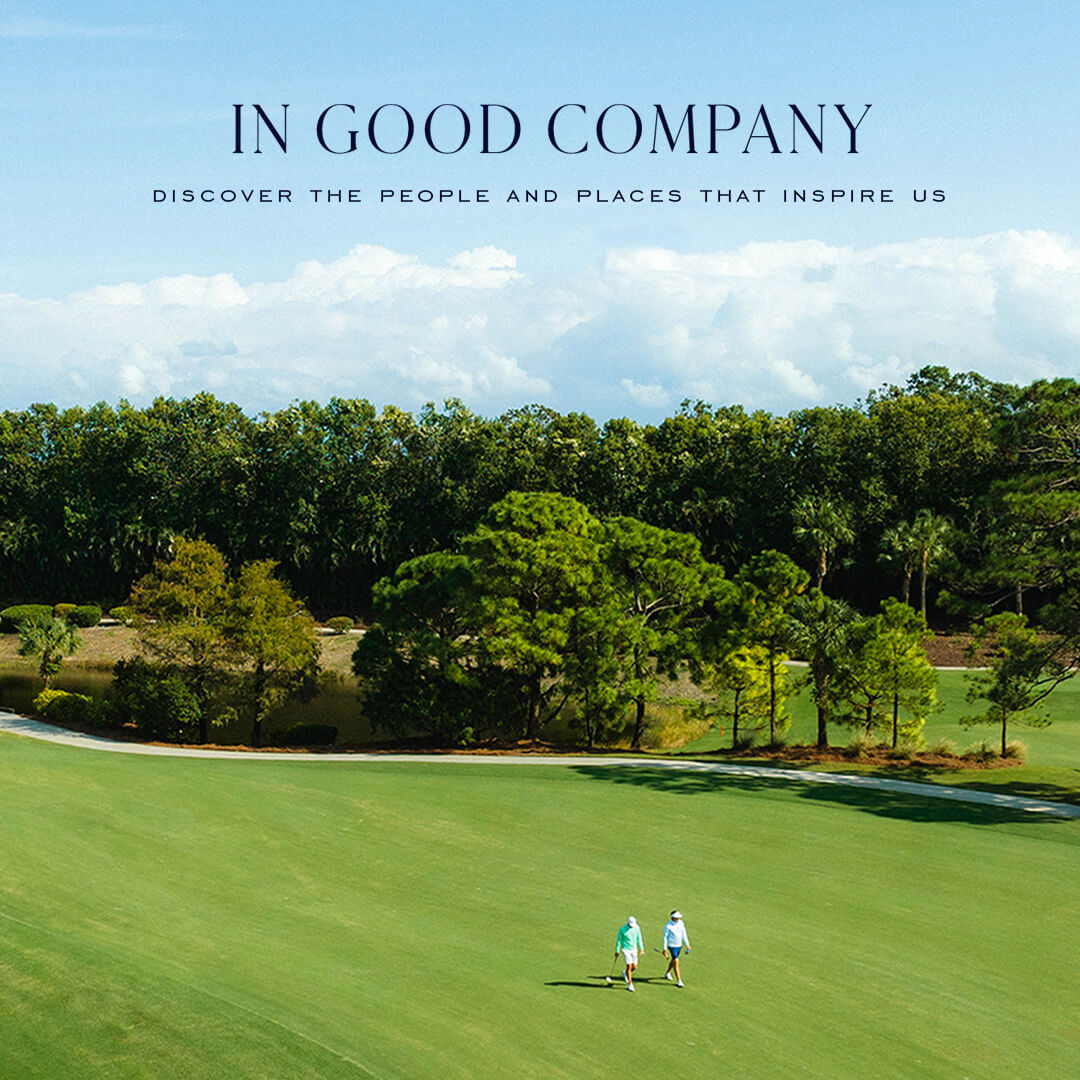 Two golfers in teal and white walking a green fairway lined with pines, under the title "IN GOOD COMPANY" and "DISCOVER THE PEOPLE AND PLACES THAT INSPIRE US".