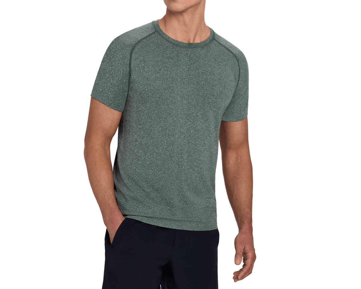 Model wearing The Pickett Performance T-Shirt: Heathered Cypress, a short-sleeve raglan tee with a crew neck and tonal green seams, styled with navy shorts.