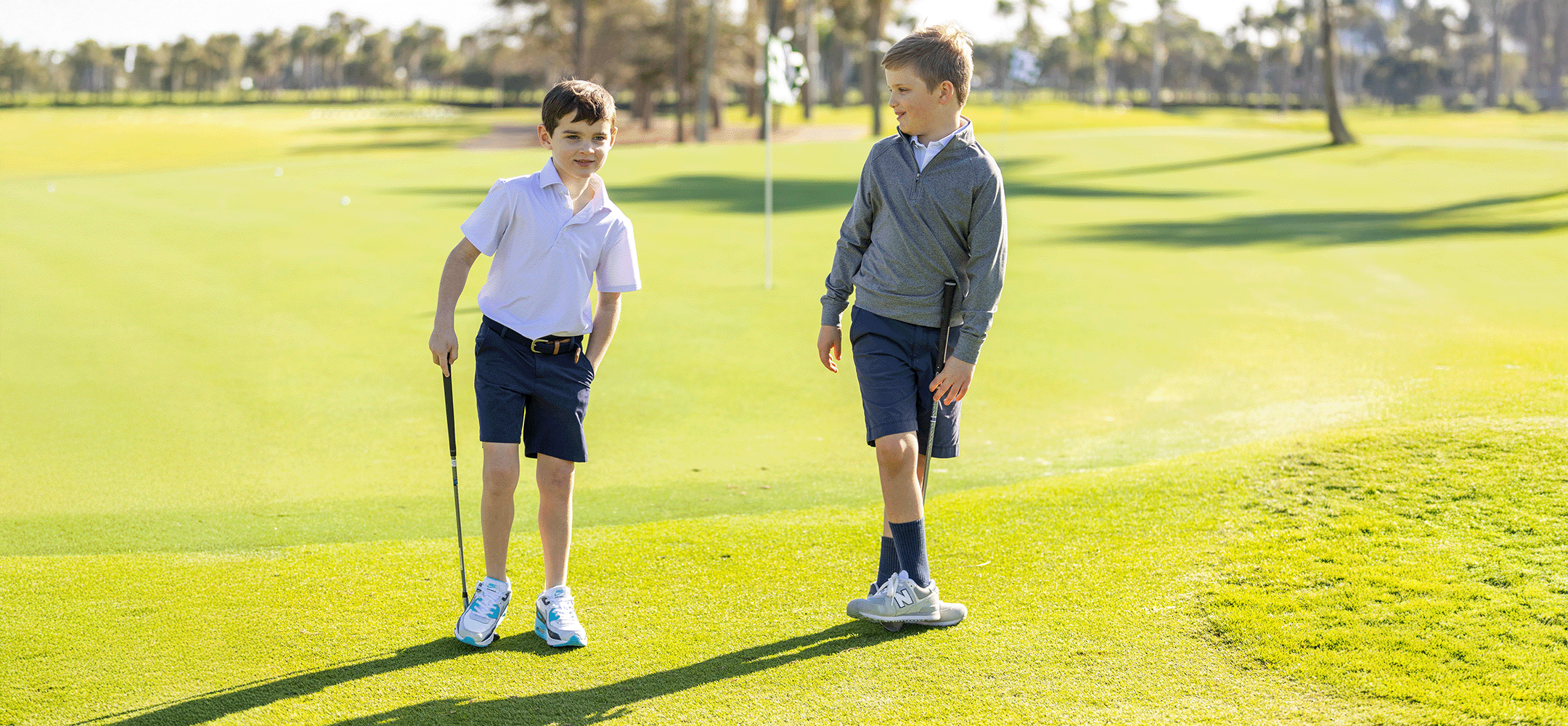 Two boys on a golf course with golf clubs