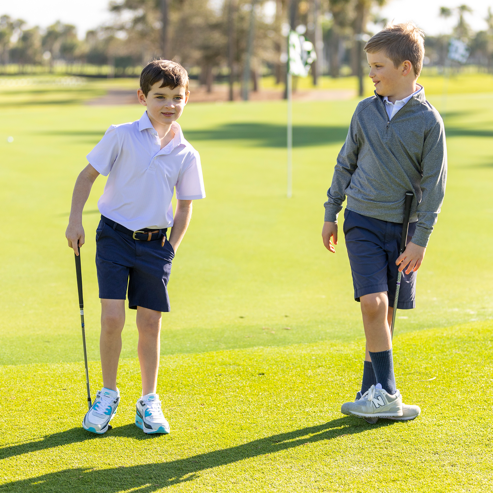 Two young boys on a golf course with golf clubs