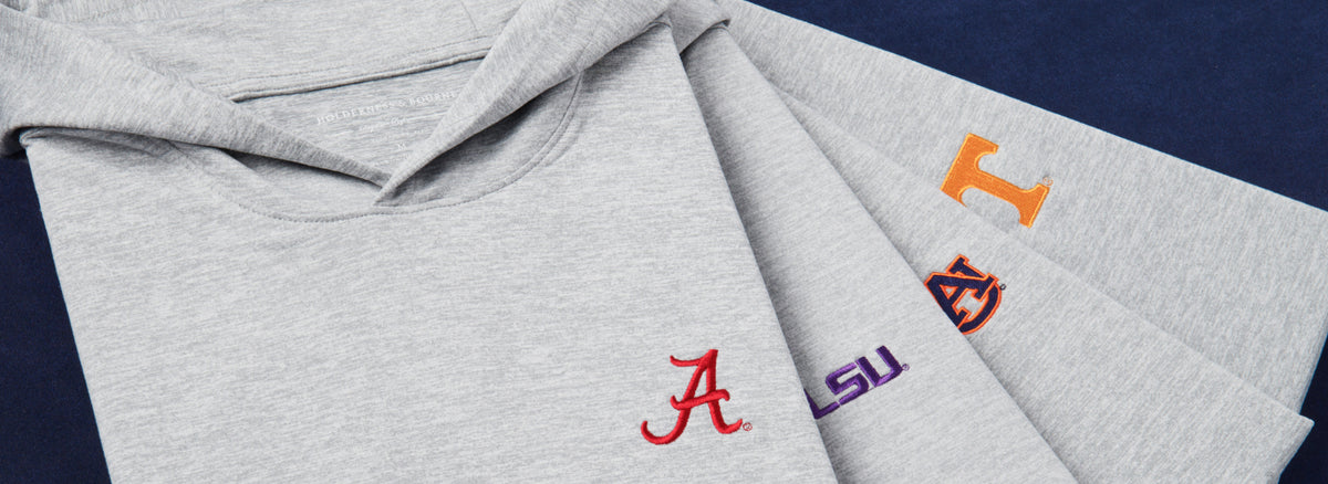 Gray hoodies fanned out with embroidered Alabama, LSU, Auburn and Tennessee logos on a navy background.