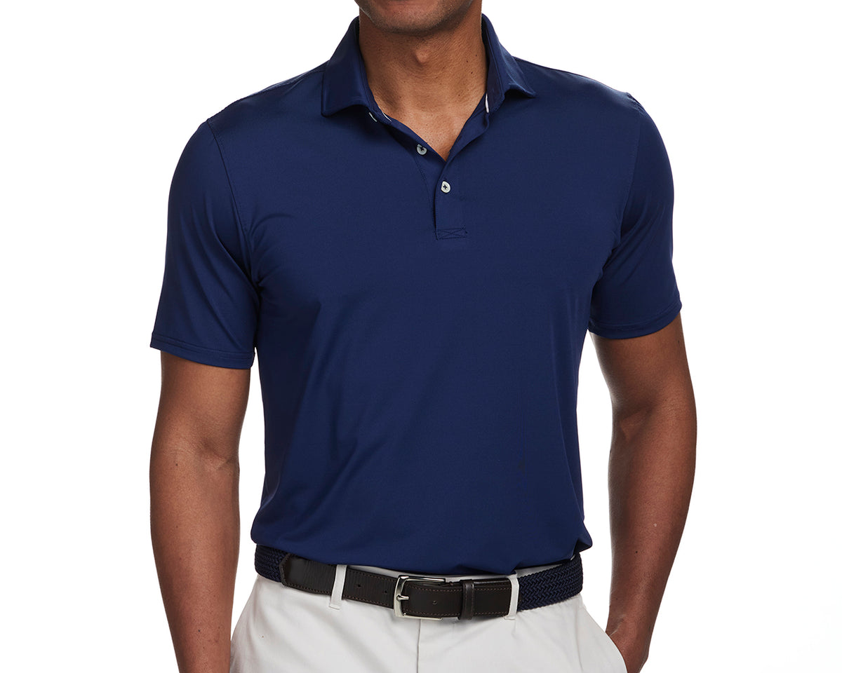 Model wearing The Anderson Shirt: Navy, a comfortable polo with a structured spread collar, tucked into light trousers with a black belt.
