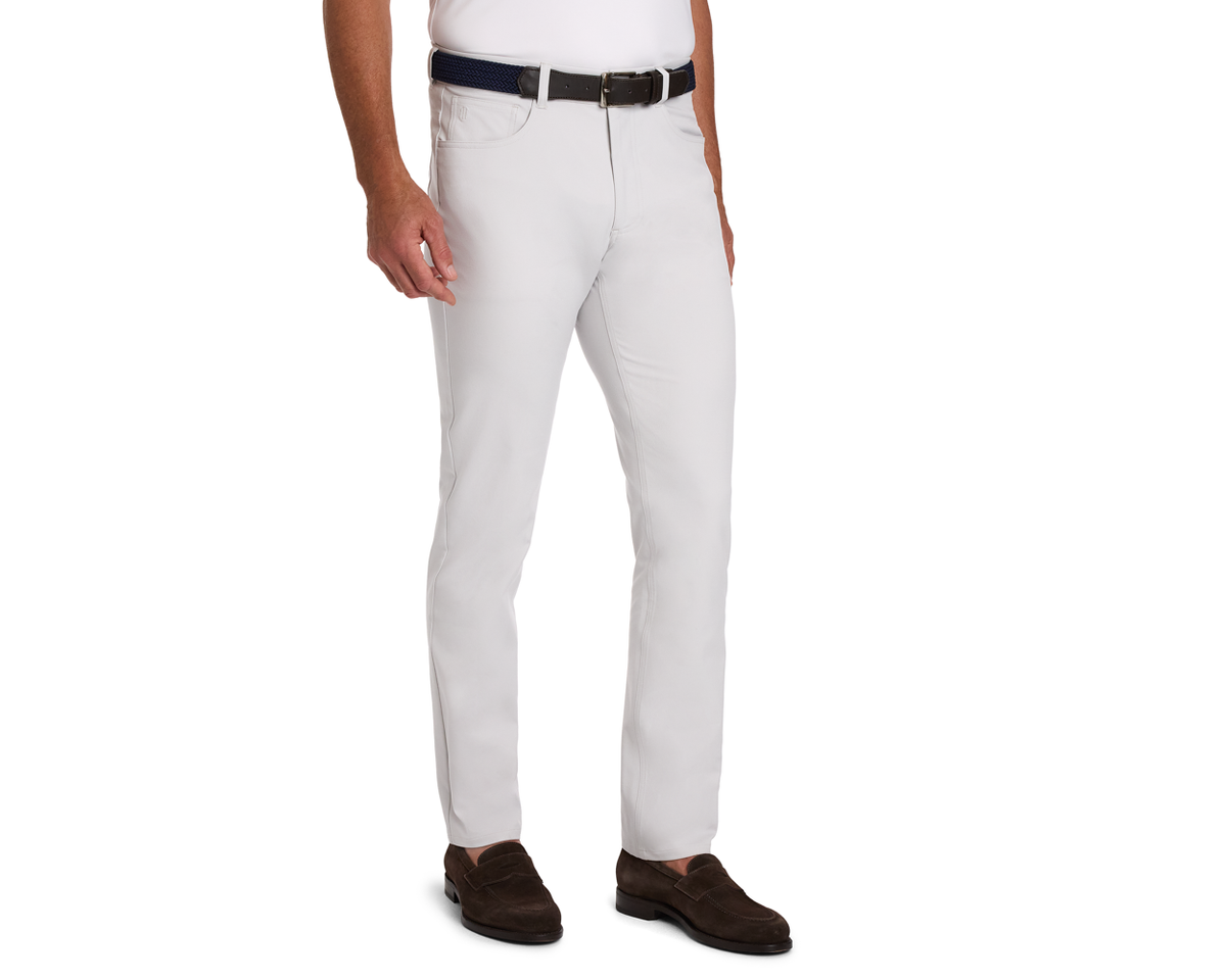 The McDaniel 5 Pocket Pant: Stone showcased in a slim-fit style with a dark woven belt, paired with a white shirt and dark brown loafers.