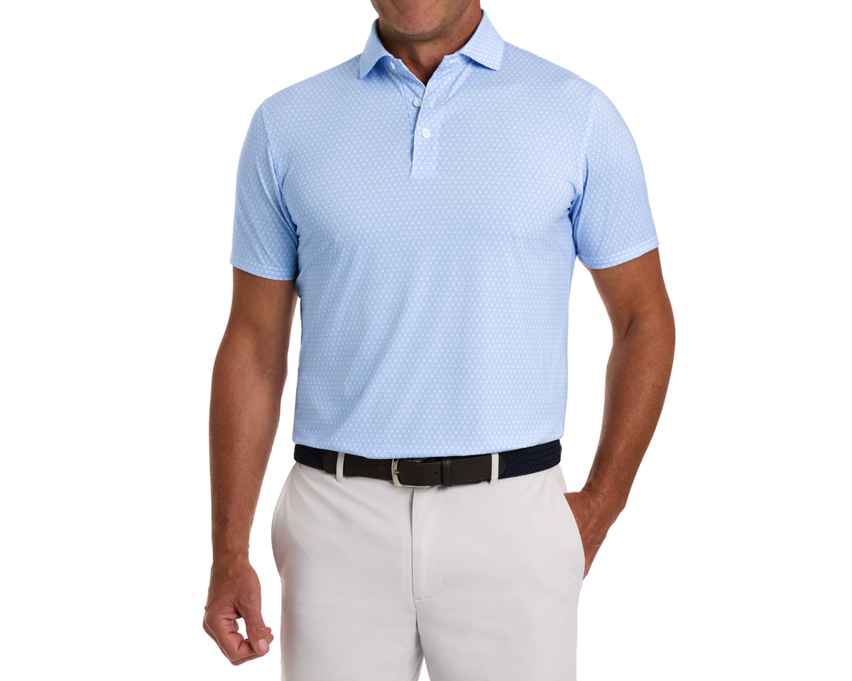 The Griffin Shirt: Horizon Blue, featuring a subtle griffin pattern, worn with light trousers and a navy woven belt, highlighting its versatile, performance-focused design.