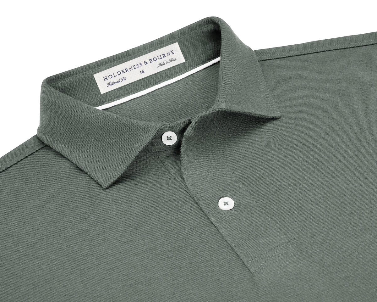 The Neville Shirt: Ivy, featuring a green polo design with a collar, two white buttons, and a label indicating HOLDERNESS & BOURNE, Tailored Fit, M, Made in Peru.