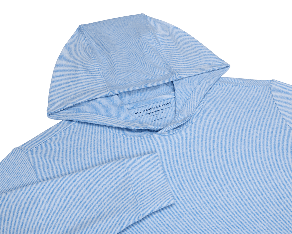 The Hamilton Hoodie: Heathered Horizon Blue & White, showcasing a light-blue, thinly striped design, hood, shoulder seams, and sleeve, crafted for comfort with 4-way stretch and UPF 50+ protection.