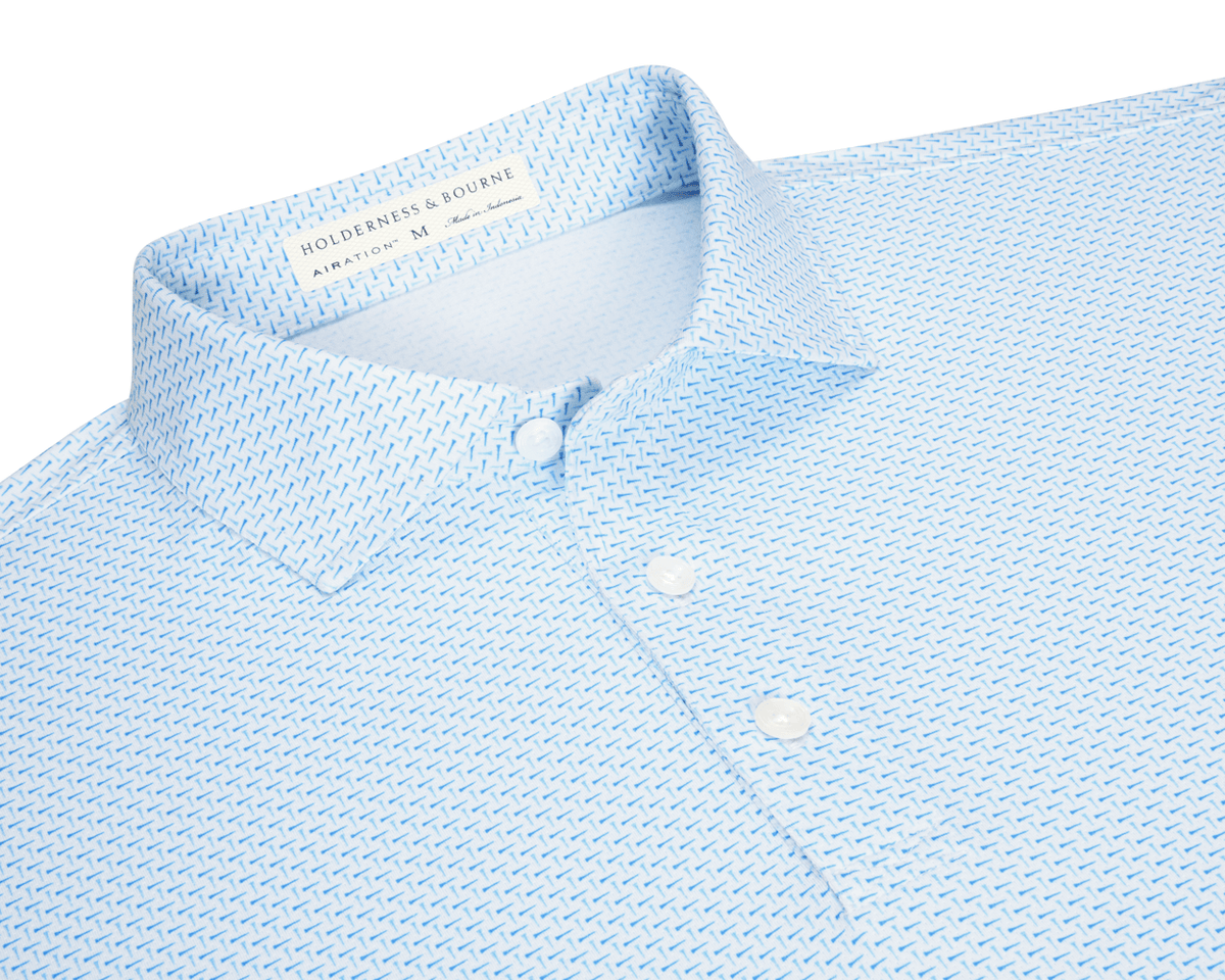 The Cromwell Shirt: Vista Blue & Horizon Blue, features a geometric print, white buttons, and a structured collar, made from AIRATION® fabric for breathability and comfort.