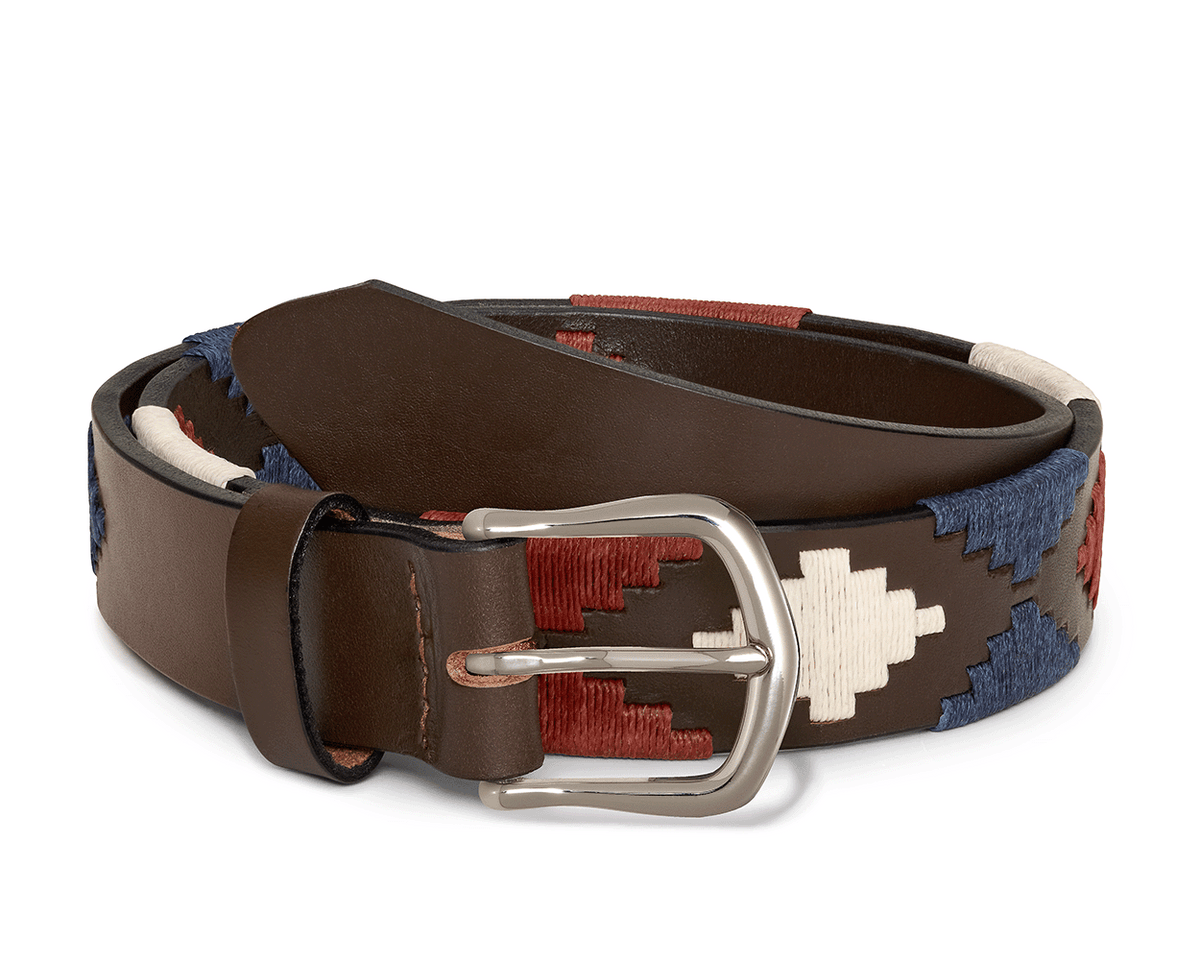 The Barker Belt: Brown/Navy/Claret/Stone features a rolled brown leather strap with a silver-tone buckle and intricate Southwestern-style geometric patterns in red, white, and blue.