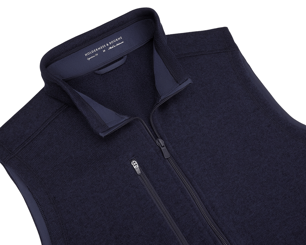 The Ashby Vest: Heathered Dark Navy by Holderness & Bourne, featuring a zip-up design, zippered chest pocket, and brushed interior for comfort and style.
