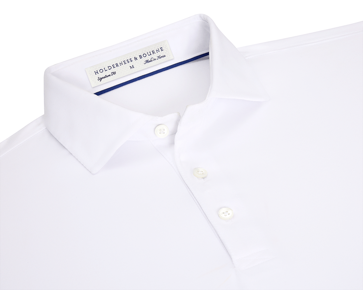 The Anderson Shirt: White, short-sleeved polo with structured spread collar, three-button placket, and performance fabric for stretch and moisture wicking. Size M, made in Korea.