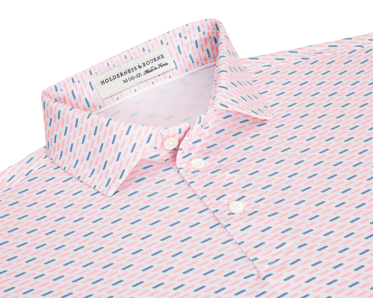 The James Boys Shirt: Cape & Andover features a light polo with coral and navy dash pattern, structured collar, and three white buttons.