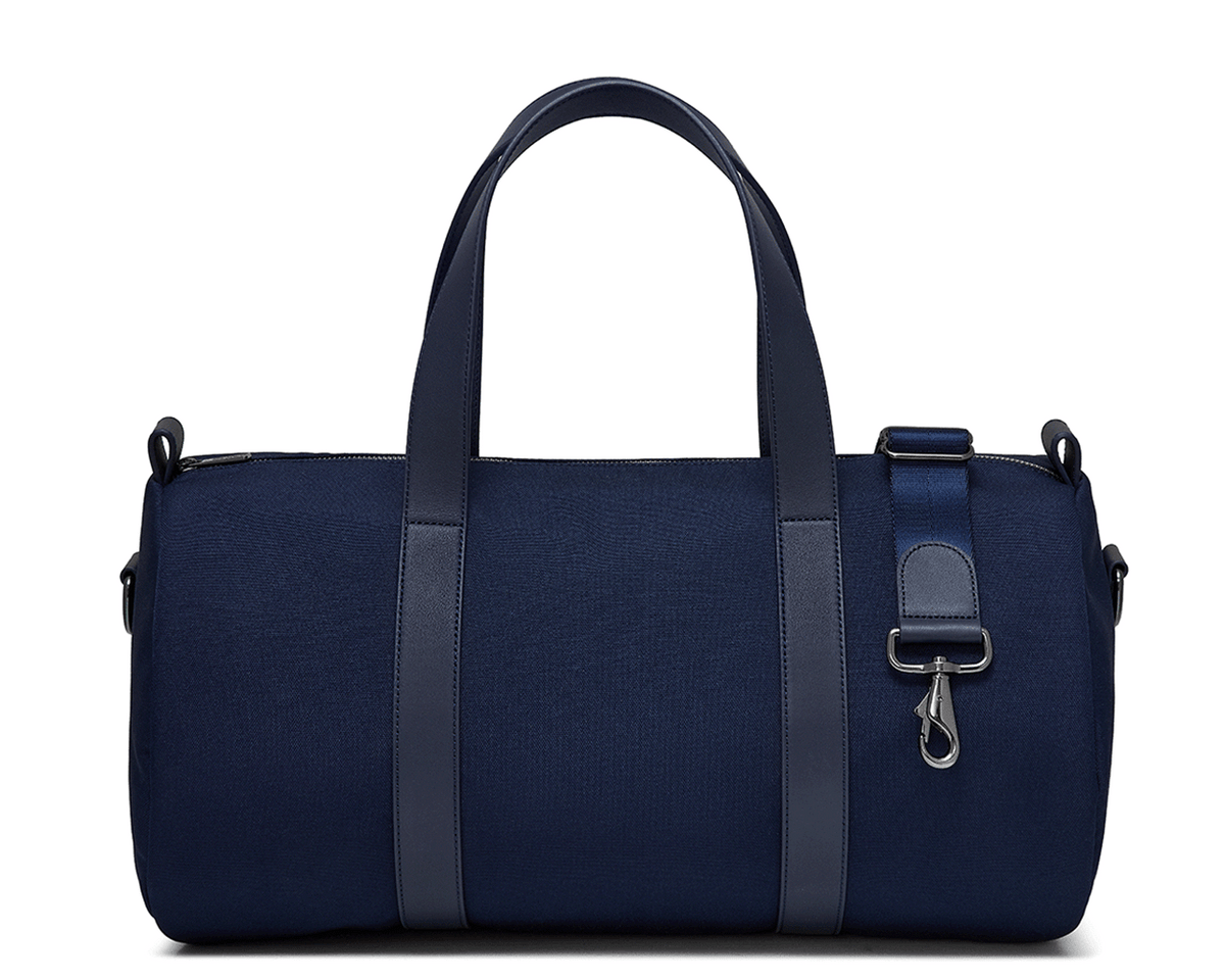 The Marston Banker Bag: Navy Ballistic, featuring top carry handles, adjustable shoulder strap, Napa leather trim, oxford stripe lining, and gunmetal hardware. Ideal for gym or travel.