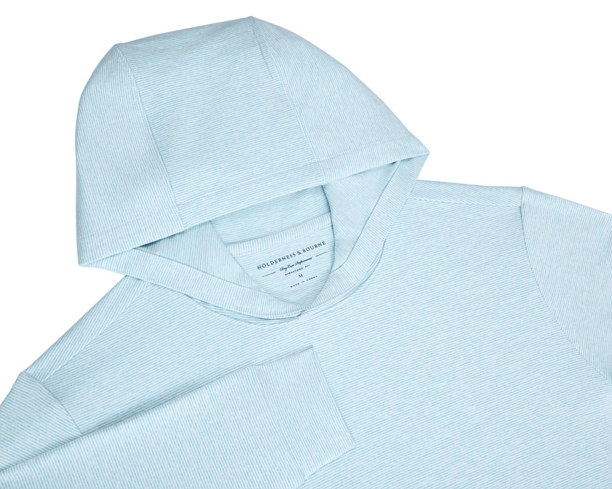 The Hamilton Hoodie: Heathered Harbor & White, light-blue with fine white pin-stripes, features a hood, sleeve, and Holderness & Bourne tag, offering comfort and UPF 50+ protection.