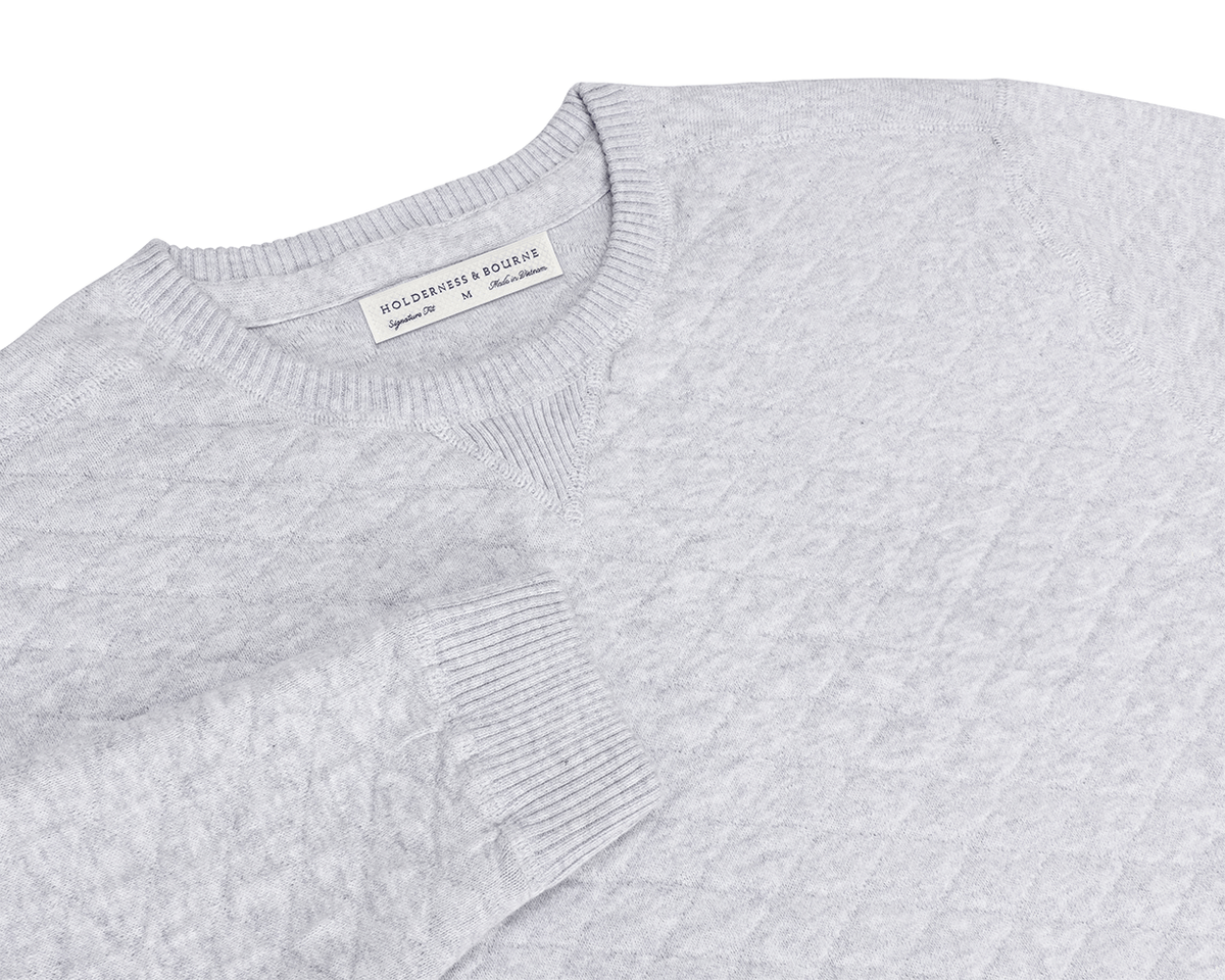 The Ward Crewneck Sweater: Heathered Gray features a textured knit pattern, ribbed details, V-stitch accent, and a Holderness & Bourne label inside the collar.
