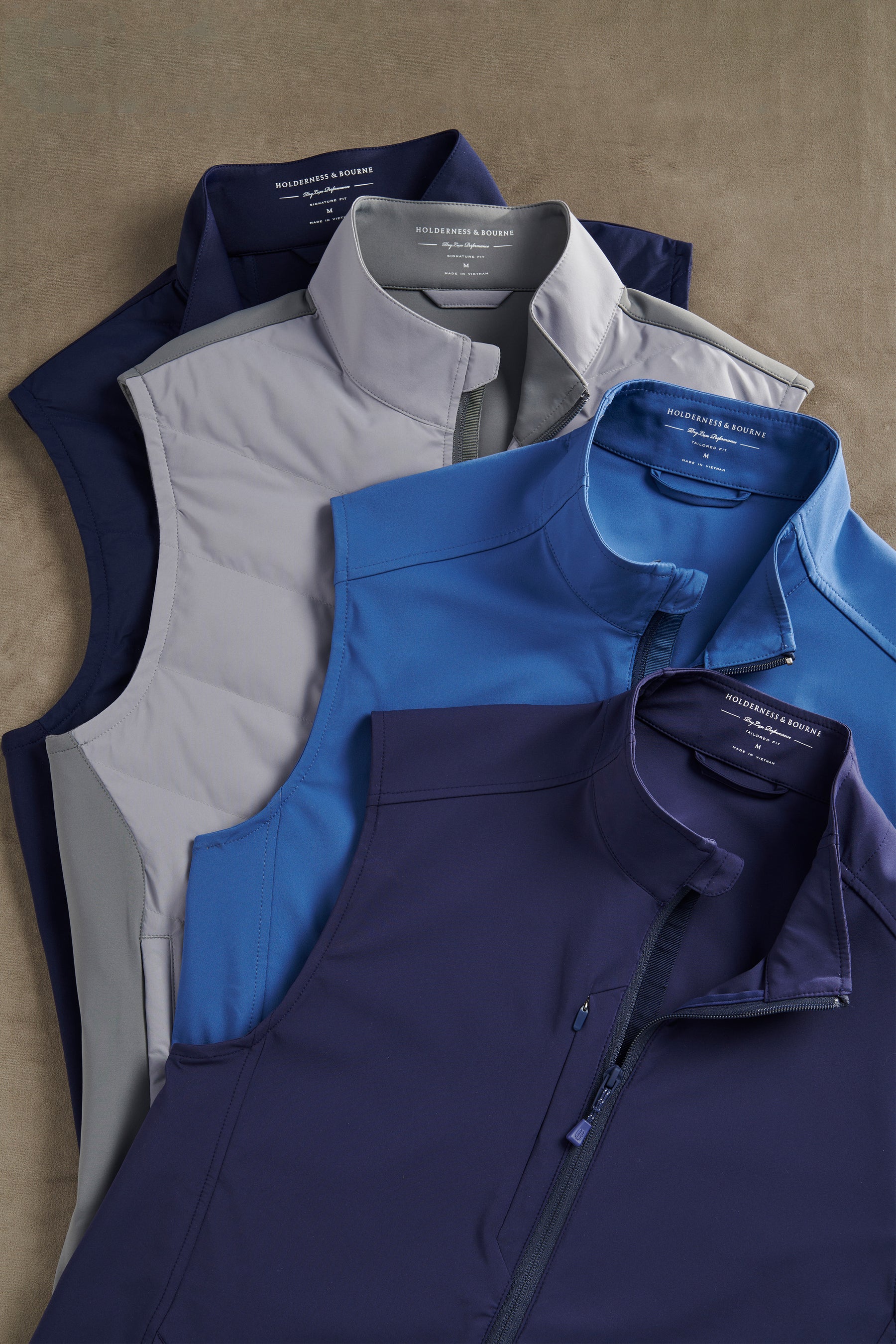 Collection of blue and gray jackets and vests on a beige surface