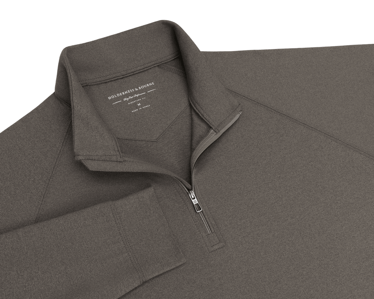 Close-up of The Westland Quarter-Zip: Heathered Driftwood showing the quarter-zip, raglan sleeve seam, collar, and Holderness & Bourne neck label.