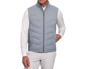 Man wearing The Benton Vest: Gray, showcasing its quilted, zip-front design with Thermore® insulation, hand in pocket, over a white shirt.