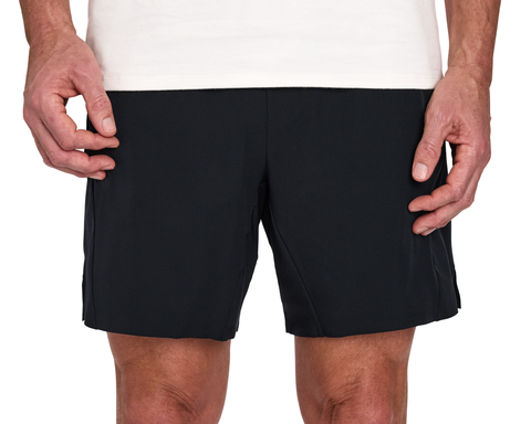 Person wearing The Saunders Short: Black, featuring a quick-drying tech blend and four-way stretch, with hands resting at sides.