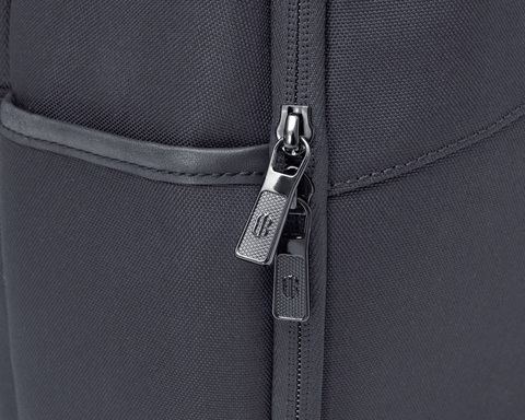 Close-up of The Broughton Backpack: Dark Gray showing the woven ballistic nylon, gunmetal zipper pulls, and leather-trimmed pocket edge.