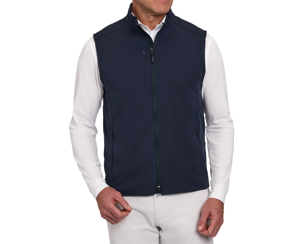 Model wearing The Boyd Vest: Navy, featuring a high collar, full-length double zipper, and chest pocket, layered over a white shirt and light trousers.