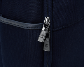 Close-up of The Broughton Backpack's silver zipper pulls on navy fabric, highlighting its durable, stylish design with leather and gunmetal chrome trim.