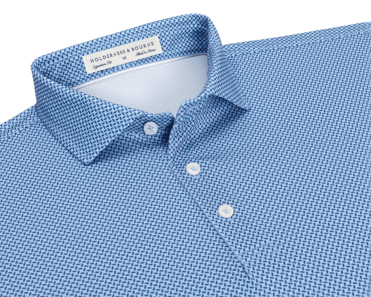 The Collins Shirt: Vista Blue & Pacific Blue flat-lay showing its spread collar, three-button placket, and interior label, with a geometric pattern on performance pique.