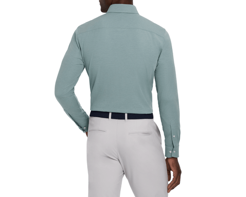 Back view of a model wearing The Cullinane Shirt: Heathered California Spruce, showing the plain back, yoke seam, light gray pants, and woven belt.