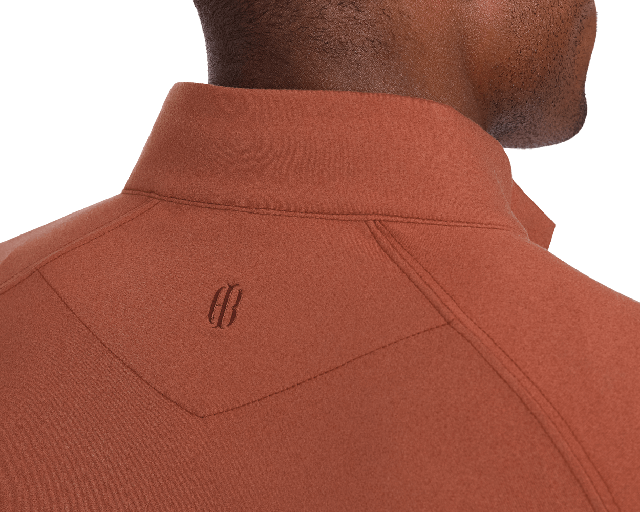 Close-up of The Westland Quarter-Zip: Heathered Russet, featuring a small logo below the collar on a burnt-orange peached fabric, highlighting its moisture-wicking performance.