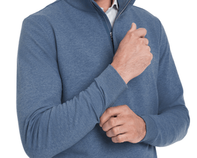 Person wearing The Harper Quarter-Zip: Heathered Bedford, showcasing its ribbed cuffs and collar zip, highlighting the sweatshirt's plush, shape-retaining design over a white shirt.