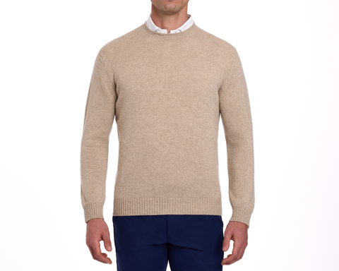 The Berwick Crewneck Sweater: Heathered Dune, made from plush Scottish cashmere, worn over a white shirt with navy trousers, showcasing classic and durable design.