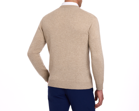 Back view of The Berwick Crewneck Sweater: Heathered Dune, showcasing plush cashmere, classic crewneck, and reinforced cuffs over a white shirt, paired with navy trousers.
