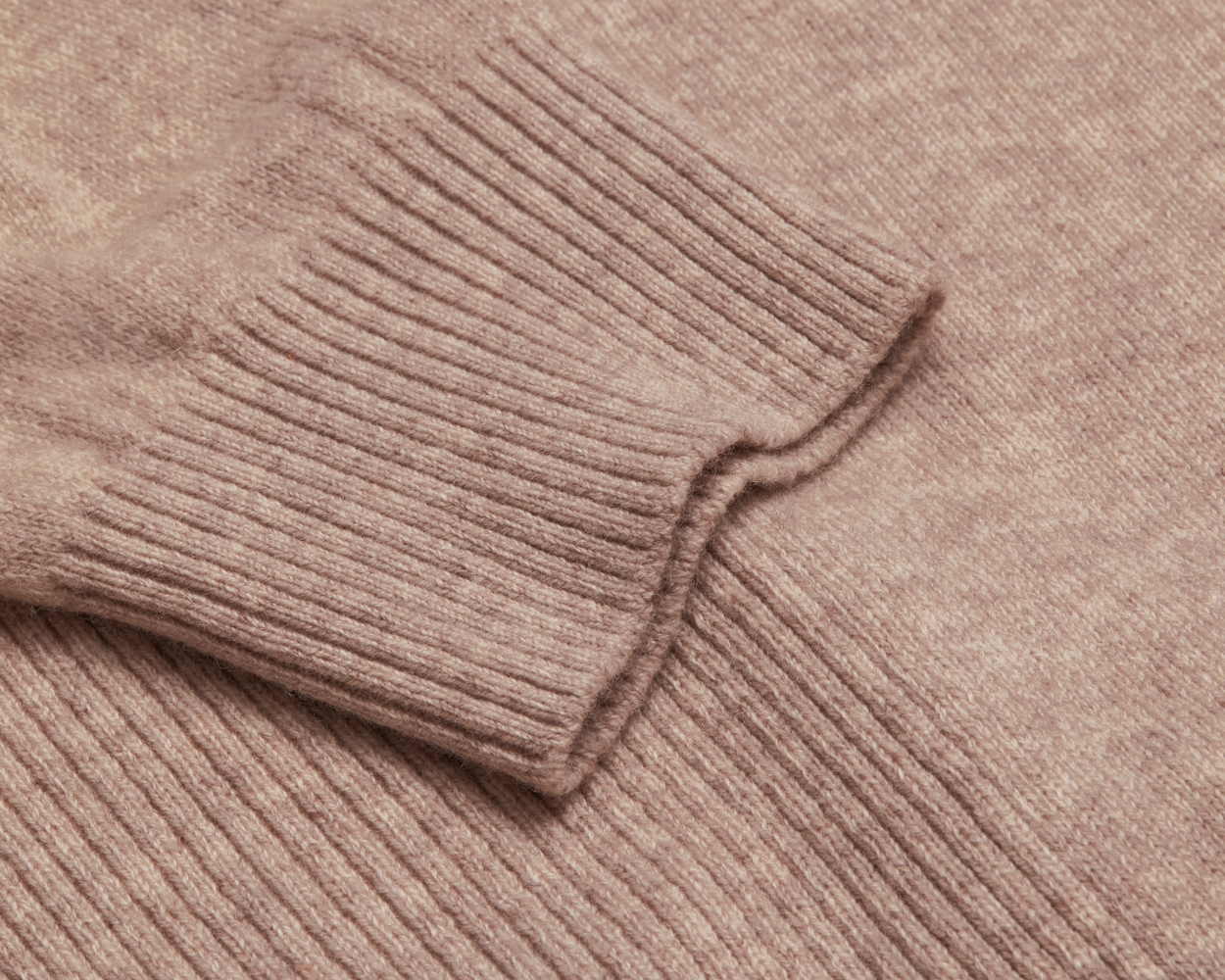 The Logan Hoodie Sweater: Heathered Dune, showcasing a ribbed cuff and woolly texture, crafted from luxurious Merino wool and cashmere for softness and warmth.
