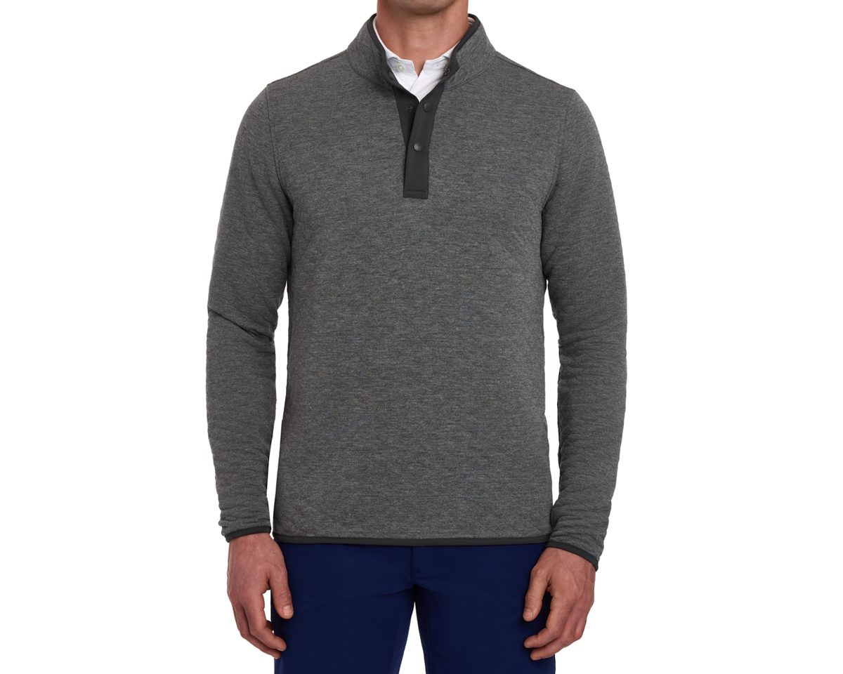 Model wearing The Sullivan Quarter-Snap: Heathered Charcoal pullover with snap-button placket, layered over a white collared shirt, paired with dark navy trousers.