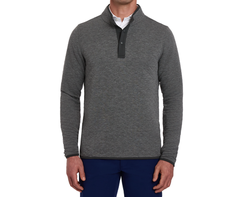 Model wearing The Sullivan Quarter-Snap: Heathered Charcoal pullover with snap-button placket, layered over a white collared shirt, paired with dark navy trousers.