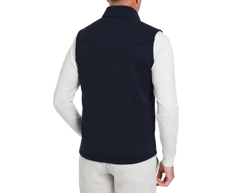 Back view of The Ashby Vest in Heathered Dark Navy, featuring a stand-up collar, V-shaped yoke, over a white shirt and light pants.