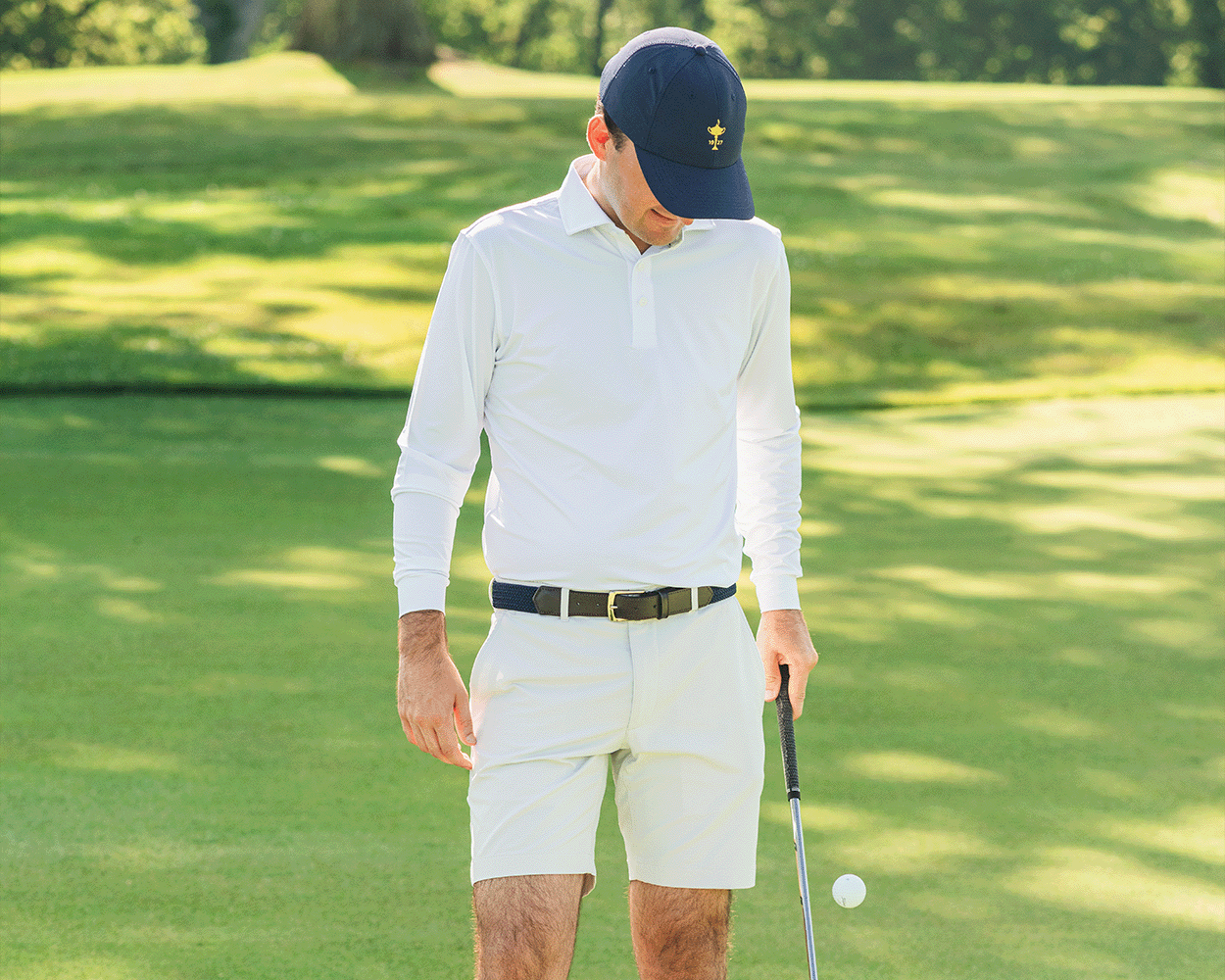Man on golf green in The Farrell Shirt: White, featuring long sleeves, spread collar, and holding a putter, highlighting comfort and performance.