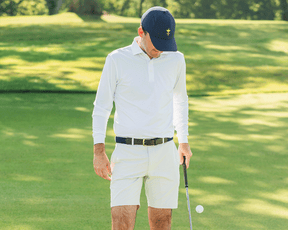 Man on golf green in The Farrell Shirt: White, featuring long sleeves, spread collar, and holding a putter, highlighting comfort and performance.