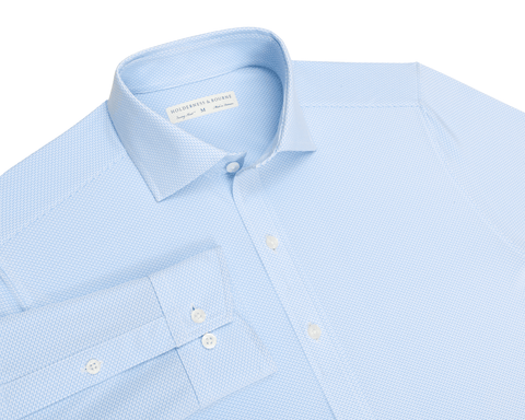 Flat-lay of The Goodrich Shirt: Vista Blue showing the spread collar, button placket, buttoned cuffs, and subtle tonal geometric weave.