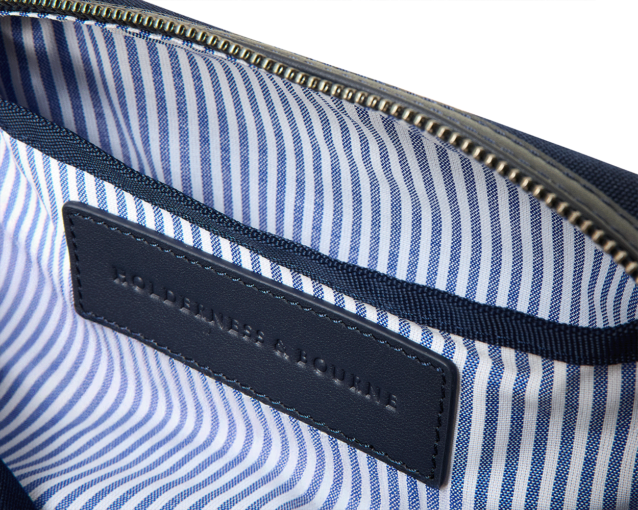 The Littler Dopp Kit: Navy Ballistic - Slate Blue Embroidery, featuring a navy zipper, blue-striped lining, and leather nameplate inside, ideal for stylish travel organization.