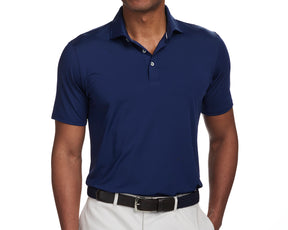Model wearing The Anderson Shirt: Navy, a comfortable polo with a structured spread collar, tucked into light trousers with a black belt.