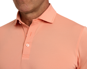 Man wearing The Macdonald Shirt: Nectarine, a light peach polo with a structured collar and contrast piping, showcasing breathable, lightweight fabric for warmer weather.