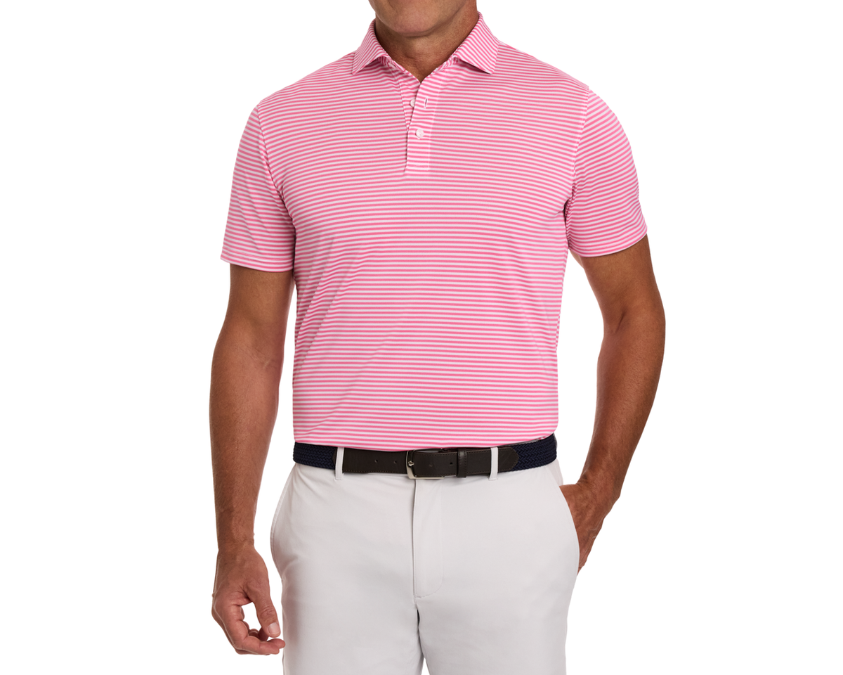 Man wearing The Maxwell Shirt: Belmont & White, a short-sleeve polo with pink and white stripes, paired with off-white trousers and a dark belt.