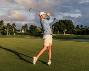 Man in a golf swing wearing The Westland Quarter-Zip: Heathered Vista Blue, showcasing its lightweight, moisture-wicking fabric on a sunny golf course.