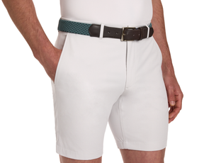The Fischer Belt: Dark Harbor & Navy Basketweave shown on light-colored tailored shorts, featuring a woven teal design with leather ends and a brass-tone buckle.