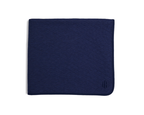 The Van Pelt Blanket: Heathered Navy; a folded, navy blanket with a piped border and tonal embroidered logo, ideal for cozy evenings.