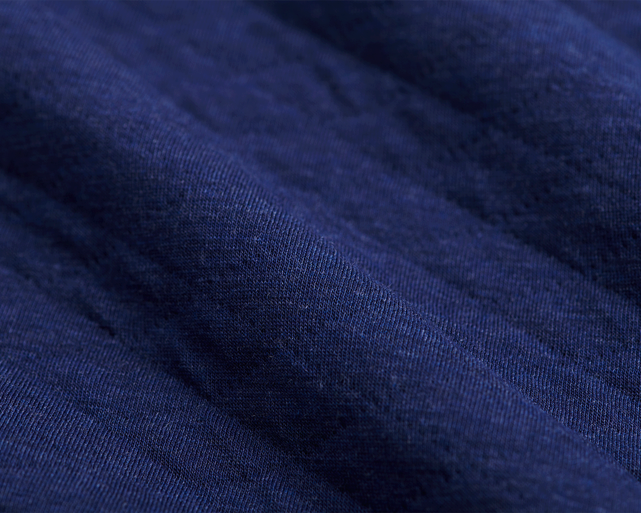 Close-up of The Van Pelt Blanket: Heathered Navy, showcasing its dark-blue, finely knit fabric with gentle folds, perfect for cozy evenings.