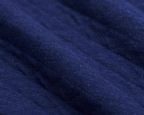 Close-up of The Van Pelt Blanket: Heathered Navy, showcasing its dark-blue, finely knit fabric with gentle folds, perfect for cozy evenings.