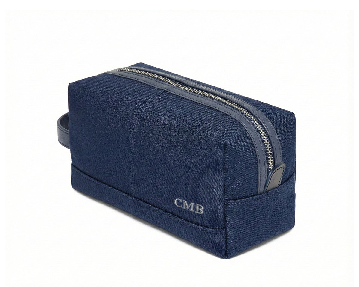 The Littler Dopp Kit: Navy Ballistic - Slate Blue Embroidery, features a rectangular navy-blue canvas with a metal zipper, monogram CMB, and a small handle.