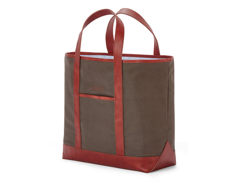 The Travis Tote Bag Cotton Twill: Dark brown canvas with reddish-brown leather trim, blue-striped lining, monogrammed CMB, exterior pocket, open-top, versatile for various uses.